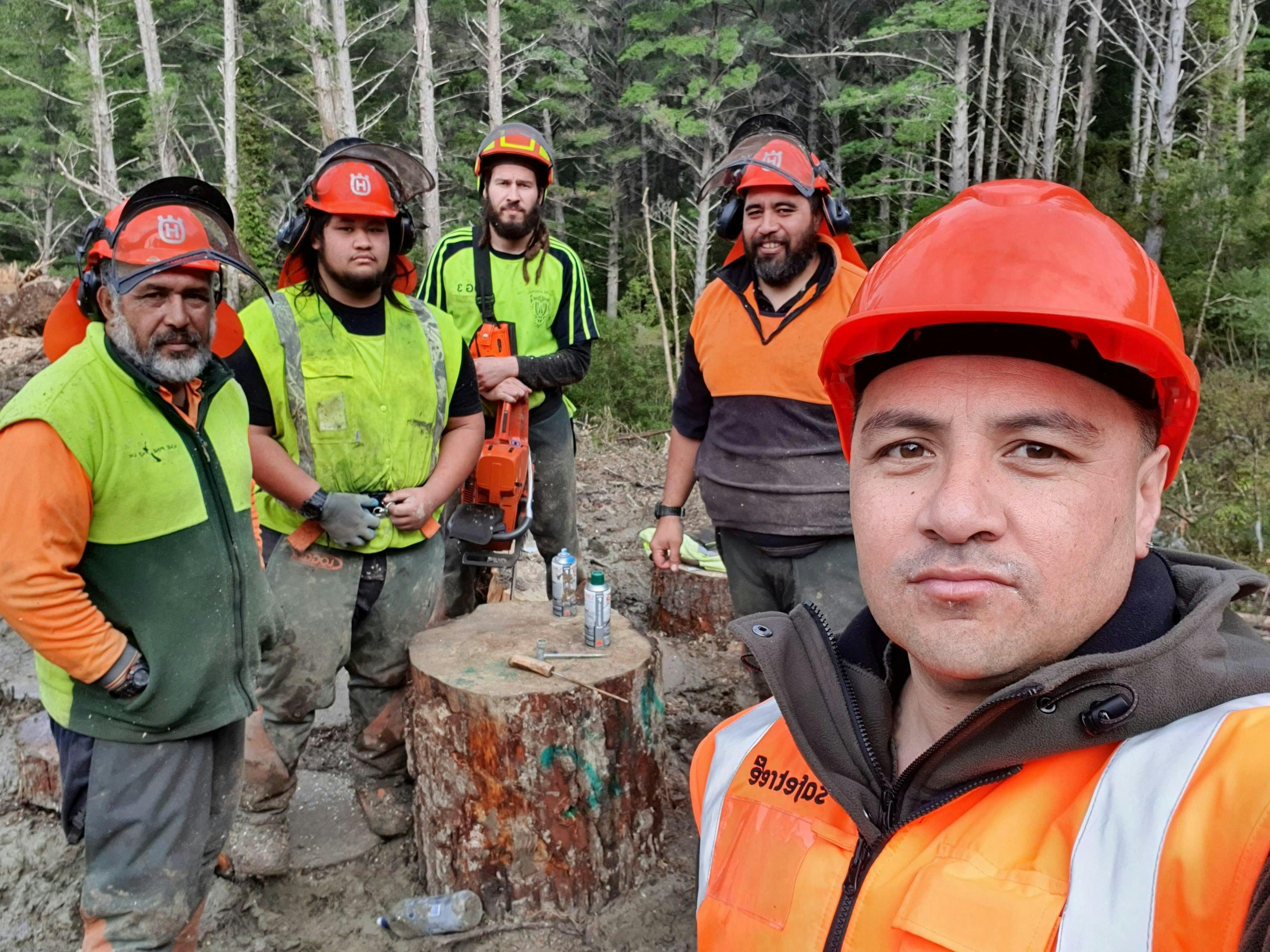 Selfie of workers resting around tree stump.
